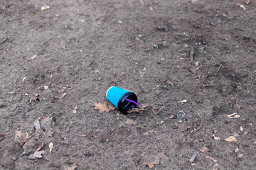 A used coffee cup with a straw was thrown to the ground