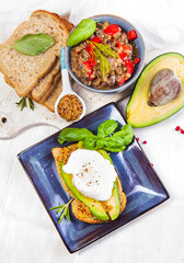 Healthy andwoch with avocado, figs and eggs - sliced avocado and egg on toasted bread with basil and rosemary for healthy breakfast or snack.