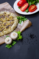 Pie with stewed potatoes and mushrooms on black background