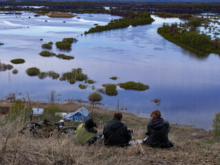 People on the bank are watching the flood of the river. A painting suggestive of the beauty and indomitability of natural phenomena