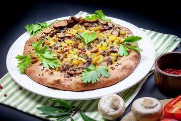 Pie with stewed potatoes and mushrooms on black background