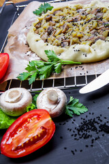 Pie with stewed potatoes and mushrooms on black background