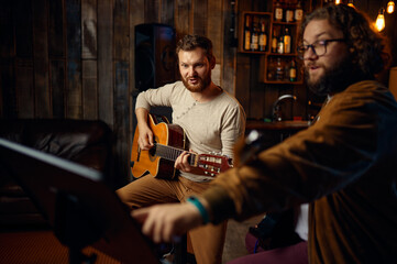 Teacher giving guitar lesson to young guy