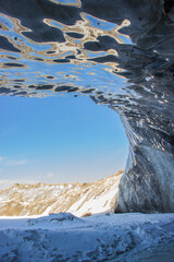 Oktyabrskaya cave of the Bogdanovich glacier in Kazakhstan. View from within and blue cloudy sky.