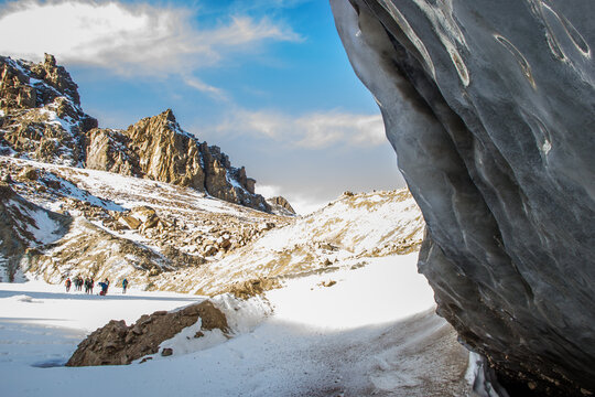 Oktyabrskaya Cave Of The Bogdanovich Glacier In Kazakhstan. View From Within And Blue Cloudy Sky.