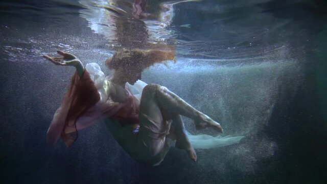 amazing beautiful woman is floating underwater, slow motion shot, beauty and grace of young lady