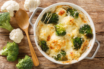 Casserole Cauliflower and broccoli baked with cheese sauce in a pot close-up on a wooden table....