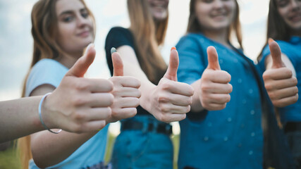 A group of girls girlfriends show thumbs up.