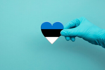 Medical workers hand wearing surgical glove holding Estonia flag heart