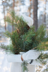 beautiful brunette girl posing with a winter bouquet of pine needles and spruce branches on the background of the forest. Life style outside the city and preparation for the new year.