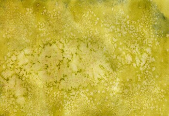 Bright watercolor textured background of yellow-olive color with speckles. Salt Effect