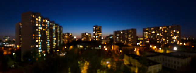 Defocused cityscape background, blurred city lights bokeh, summer evening deep blue sky over the town residential district, panorama