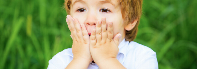 Funny child boy with hands close to face isolated on green background. Child expressing surprise...