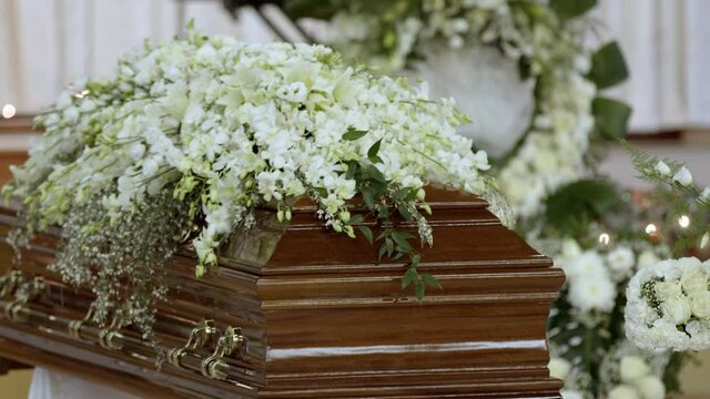 A closeup of a casket with fresh white flowers during the Vietnamese funeral ceremony in 4K