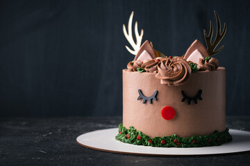 Funny reindeer cake with brown cream cheese frosting decorated with antlers on the black background. Merry Christmas and Happy New Year © alexanderon