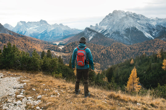 Young man standing on a top of the mountains with the beautiful view. Autumn Dolomites in the Italy.