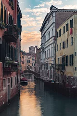 Poster Verticale opname van een kanaal omringd door gebouwen van Venetië in Italië bij zonsondergang © Denis Scarpante/Wirestock