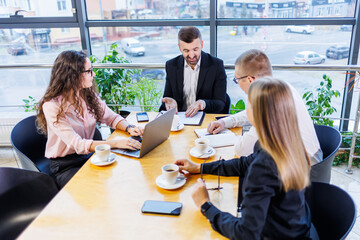 Happy business people looking at laptop presentation, success at work, sitting in modern office. Successful online negotiations. Businessmen share their knowledge