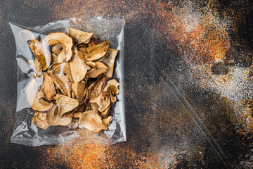 Dried mushrooms, on old dark rustic background, in plastic pack, top view flat lay , with space for text  copyspace