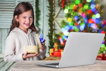 Happily surprised child looking at the laptop computer screen with Christmas background