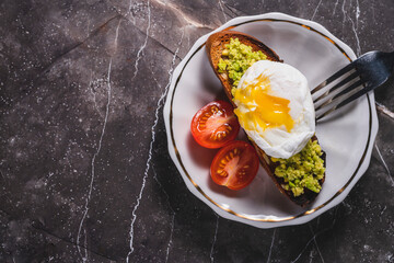 hot poached egg on toast with avocado. poached egg for breakfast. breakfast vegetarian toast with avocado and egg. vegan food