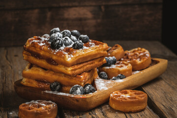 belgian waffles with berries on a dark background. sweet waffles with blueberries for breakfast