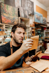 white man works in his workshop reviewing orders and shipments at his desk. small business