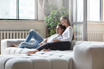 Obraz premium Happy couple is watching tv together with smile on sofa at home.