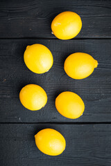 Fresh lemons, on black wooden table background, top view flat lay