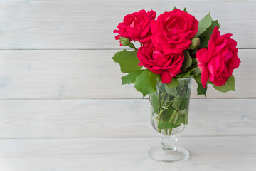 Bouquet of red roses on white wooden background, copy space. Greetings for holiday, birthday, woomans day.