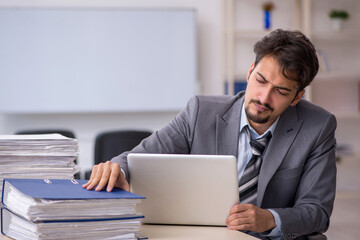 Young businessman employee and too much work in the office