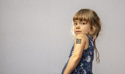 A girl with a QR code on her shoulder, gray background. Concept: vaccination of children, assignment of a QR code, people with antibodies to the virus, vaccination against coronavirus, antigen test.