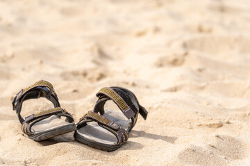 Fototapeta na wymiar Summer shoes left on the sandy shore.