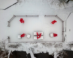 Red umbrellas in a snow-covered outdoor cafe. Aerial drone top view.