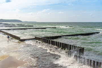 Wooden breakwater on the seashore with stones.