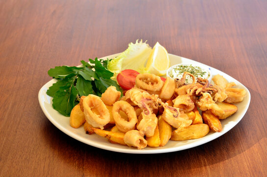 fried calamare with greens on wood table