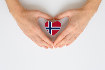 The national flag of Norway in female hands. The concept of patriotism, respect and solidarity with...