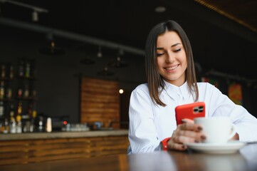 Portrait of beautiful girl using her mobile phone in cafe.