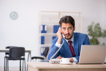 Naklejka premium Young male employee sitting at workplace