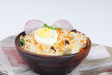 Fresh Egg biryani with a half-cut boiled egg served in a wooden bowl  isolated on white background
