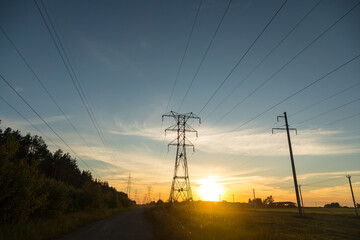 High voltage power lines in the middle of a field at sunset. Industrialization. Electrification. Power supply.