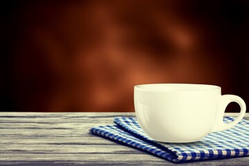 Mug with hot tea standing on a desk with blanket in a cozy room