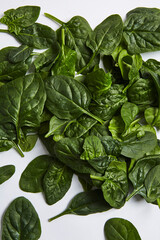 Top view of organic spinach leaves scattered on a white surface