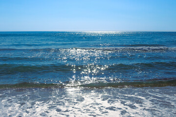 A beautiful blue sea with a wave sparkles in the sun. Natural background of nature, seascape