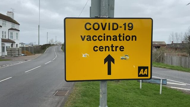 Covid-19 Vaccination Centre,  Yellow road sign directing to  Covid-19 Vaccination centre. stock footage video