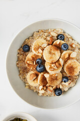 Bowl of porridge topped with banana, blueberries, almonds and cinnamon