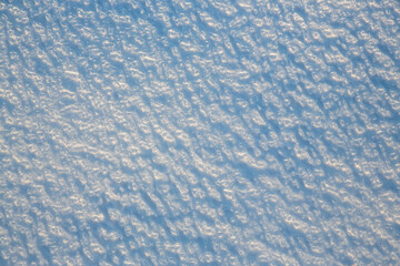 Beautiful winter background with snowy ground. Natural snow texture. Wind sculpted patterns on snow surface.