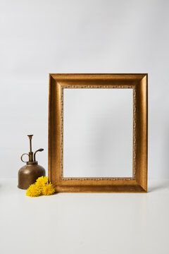 Gold picture frame still life with a brass spray bottle and dandelions