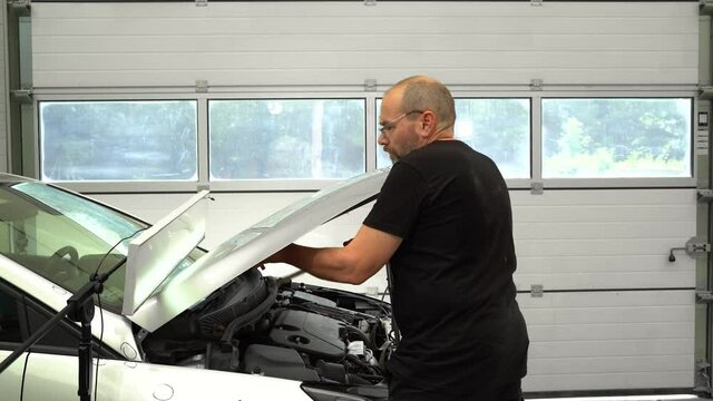 Car Body Work. Process of Repairidg Dents on Car Boby. Tecnisian is Repairing Dents After Hail On Hood Of Silver Car.