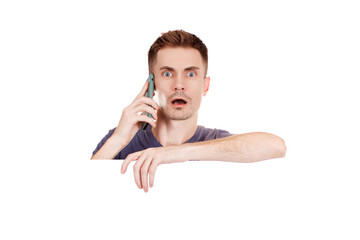 Young man with surprise on his face talking on a mobile phone on a white background. Space for text.